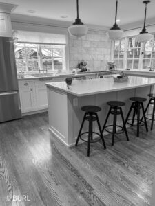 kitchen remodel black and white photo with island and inset cabinets countertop, and millwork showcasing crown.